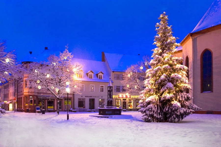 Weihnachtsstimmung auf dem menschenleeren Durlacher Marktplatz nach Neuschnee. Zu sehen sind der beleuchtete und mit Schnee gepuderte Weihnachtsbaum vor der Durlacher Stadtkirche und der Brunnen.